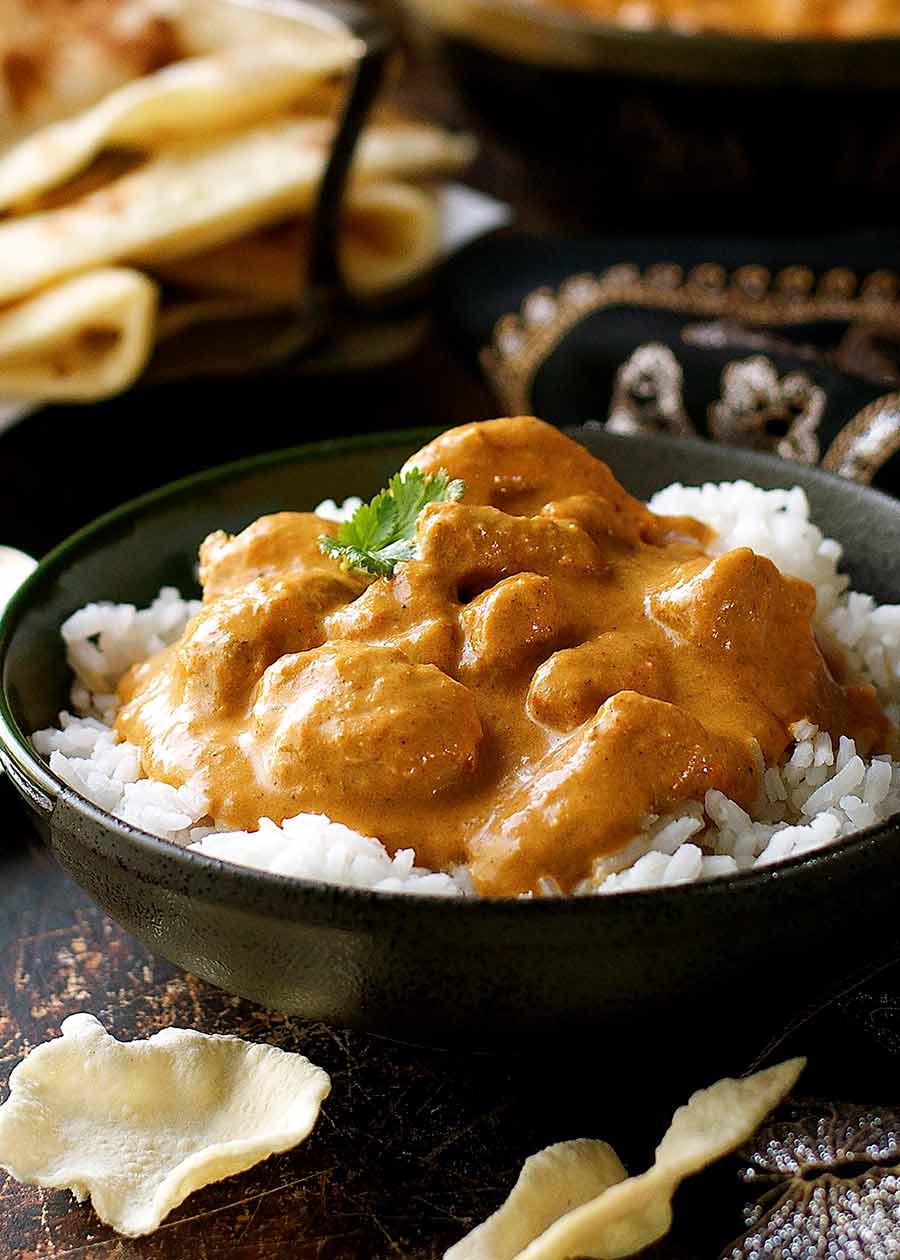 Butter Chicken on rice in a rustic black bowl, ready to be eaten