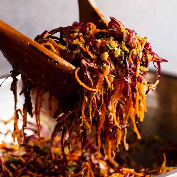 Wooden spoons tossing Cabbage and Carrot Thoran-style salad (Indian Salad)