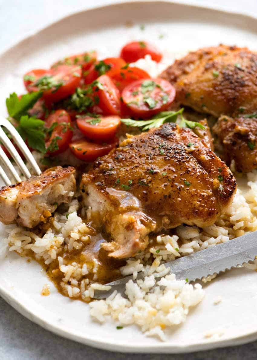 Garlic Chicken Thighs on a rustic cream plate, served over rice with a terrific quick and easy garlic butter sauce.